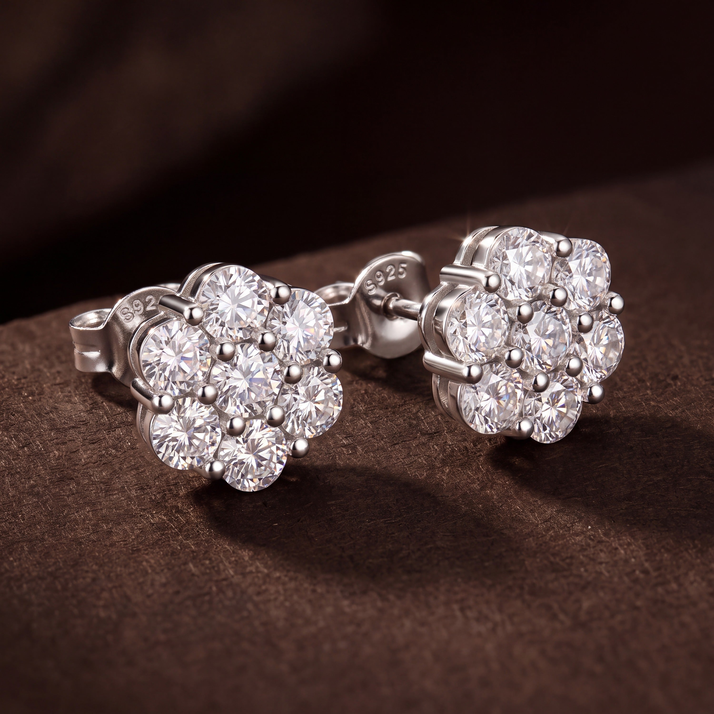 Close-up of a pair of moissanite flower cluster studs, showing the bead-prong setting and S925 stamped back
